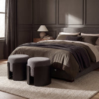 Capsula upholstered ottoman in black, styled in a room